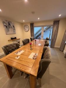 a large wooden table with chairs and a clock on the wall at Waverley Inn House in Inverness