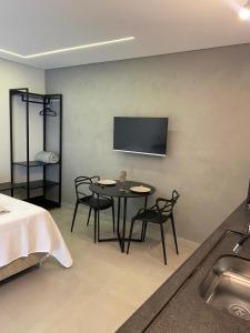 een kamer met een tafel en stoelen en een tv aan de muur bij Loft de luxo in Araxá