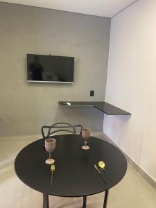 a black table with two wine glasses and a tv at Loft de luxo in Araxá