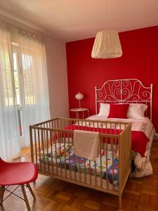 ein rotes Schlafzimmer mit einem Kinderbett und einer roten Wand in der Unterkunft 100 Contos in Porto
