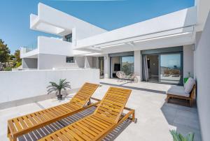 マニルバにある31 Pure South Penthouse sea views Manilvaのパティオに黄色い椅子が2脚置かれた白い家
