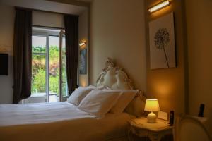 a bedroom with a white bed and a window at Villa Nonna Cicci Boutique Hotel - SPA in Cisterna dʼAsti