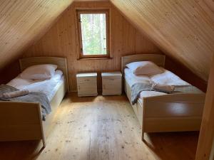 two beds in a attic room with a window at Domki Letniskowe Nad Jeziorem Kazub in Cieciorka