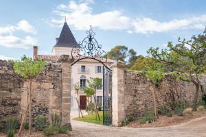 une porte dans un mur en pierre avec un château dans l'établissement Château du Parc - Gîtes & spas à Pézenas, à Pézenas