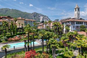 un complejo con piscina y palmeras en Hotel Beau Rivage, en Baveno