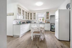 a white kitchen with a table and a refrigerator at Casa Dona Isaura in Ponta Delgada