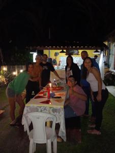 grupa ludzi stojących przy stole ze świecą w obiekcie Casa de praia cantinho do Saco 12 pessoas w mieście Angra dos Reis