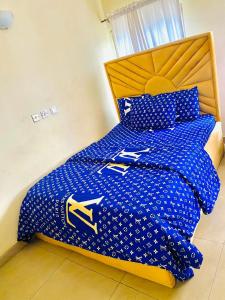 uma cama com um edredão azul com uma cabeceira amarela em Miraph Apartment em Abuja