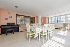 Un comedor con una mesa y sillas y un piano. en Enorme apartamiento en CALA ALTA de Villajoyosa, en Cala de Finestrat