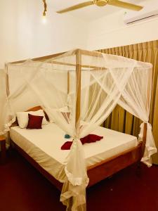 een slaapkamer met een hemelbed met een witte klamboe bij Tropicana Home Stay in Arugam Bay