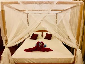 Una cama con dosel con dos animales de peluche. en Tropicana Home Stay en Arugam Bay