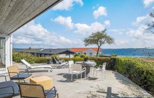 a patio with chairs and a table and the ocean at Amazing Home In Grsten With House Sea View in Gråsten