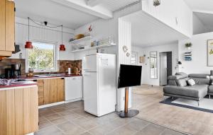a kitchen with a refrigerator and a tv in it at Amazing Home In Grsten With House Sea View in Gråsten