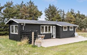 a black cabin with a deck in a field at Awesome Home In Hirtshals With Kitchen in Hirtshals