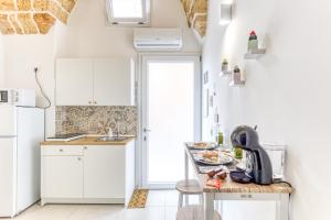 eine Küche mit weißen Schränken und einem Tisch mit Essen drauf in der Unterkunft Bilocale con vasca idromassaggio in Presicce