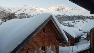 ein schneebedecktes Dach einer Hütte mit Bergen im Hintergrund in der Unterkunft Village gaulois-appt 48r in Saint-François-Longchamp