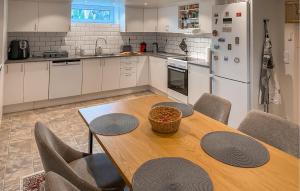 een keuken met een houten tafel met stoelen en een witte koelkast bij Amazing Apartment In Vimmerby With Kitchen in Vimmerby
