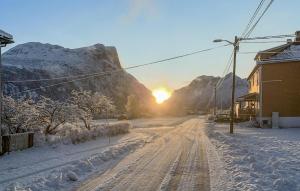 a snow covered street with the sun setting behind a mountain at 2 Bedroom Gorgeous Apartment In Eresfjord in Nauste