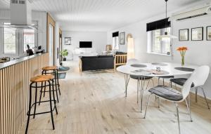 uma cozinha e sala de estar com uma mesa branca e cadeiras em Ronaldo em Strandby Gårde