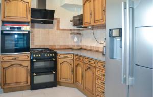 a kitchen with wooden cabinets and a stove and a refrigerator at Gorgeous Home In Marcillac-La-Croisille in Marcillac-la-Croisille