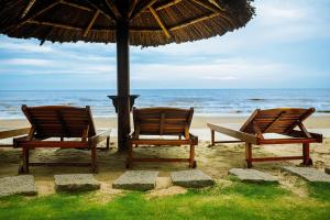 duas cadeiras sentadas sob um guarda-sol na praia em Muong Thanh Holiday Muine Hotel em Mui Ne