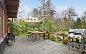 a wooden deck with a grill and a table with a barbecue at Beautiful Home In Vejby With Kitchen in Vejby