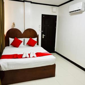 a bedroom with a large bed with red pillows at Offshore Hotel in General Santos