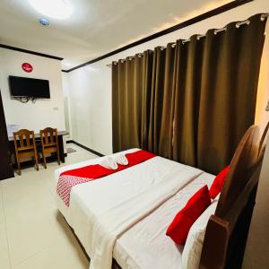 um quarto com uma cama com almofadas vermelhas em Offshore Hotel em General Santos