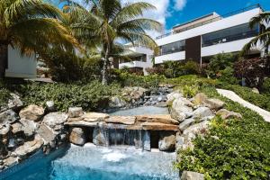 a waterfall in a garden with a building at Jan Sofat LUX - 2 swimming pools - 2 bedroom Apartment Mariposa in Willemstad