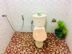 a toilet in a bathroom with a tile floor at Tropicana Home Stay in Arugam Bay