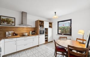 a kitchen with white cabinets and a table in it at Ferienhaus 2 Schlafzimmer in Bad Zwischenahn +10 photos