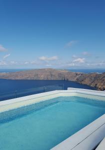 a large swimming pool in front of a blue sky at Langas Villas in Imerovigli