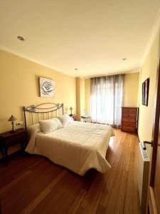 een slaapkamer met een bed en een houten vloer bij Apartamento frente al mar in Villanueva de Arosa