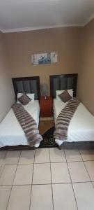 due letti uno accanto all'altro in una stanza di Marang Gardens Lodge a Mahikeng Altre 13 foto