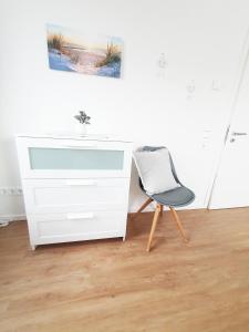 krzesło siedzące przed białą komodą w obiekcie Ferienwohnung Beste - für eine entspannte Auszeit w mieście Bad Oldesloe