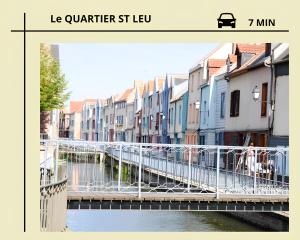 eine Brücke über einen Fluss in einer Stadt mit Gebäuden in der Unterkunft Studio Miraumont, stationnement gratuit, 5min gare in Amiens