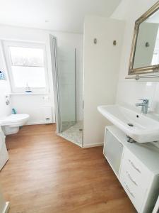 W białej łazience znajduje się umywalka i lustro. w obiekcie Ferienwohnung Beste - für eine entspannte Auszeit w mieście Bad Oldesloe