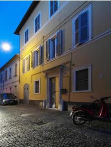 佩薩羅的住宿－皮吉奧托酒店，停在黄色建筑前面的摩托车