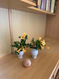 twee witte vazen met gele bloemen op een tafel bij Beautiful Penthouse Sea View - Private Terrace in Maiori