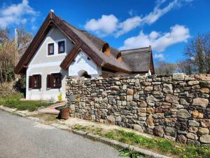 uma pequena casa atrás de uma parede de pedra em A nyugalom háza em Szentbékkálla