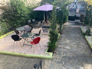 un patio con sillas, mesas y una sombrilla en Le Jardin d Inès, en Espéraza