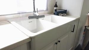 a white sink in a kitchen with a window at huisje Zilvermeeuw in Burgh Haamstede +36 photos