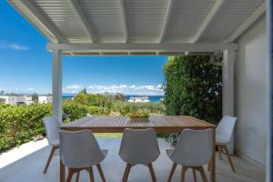 波利克罗诺NG Villas Polichrono的露台上的桌子和椅子，可欣赏海景