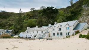 a white building on the beach next to a hill at Hen Dafarn in Nefyn