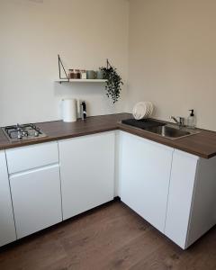 a kitchen with white cabinets and a sink at Lauku Str.Apartment in Liepāja