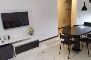 a living room with a table and a tv on a wall at Apartamento 102 do Residencial Argonauta in Bombinhas