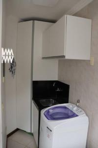 a small kitchen with a washing machine and a sink at Apartamento 102 do Residencial Argonauta in Bombinhas