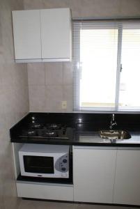a kitchen with a stove and a sink at Apartamento 102 do Residencial Argonauta in Bombinhas