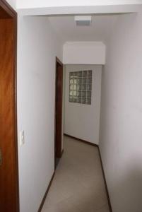 an empty hallway with a white wall and a window at Apartamento 102 do Residencial Argonauta in Bombinhas