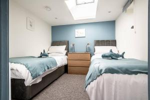 OttertonにあるPass the Keys Modern and accessible bungalow in village locationの青と白の壁のベッドルーム1室(ベッド2台付)